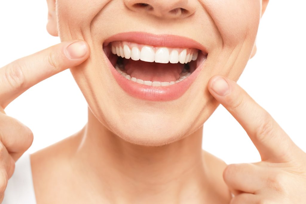 Smiling woman pointing to straight teeth